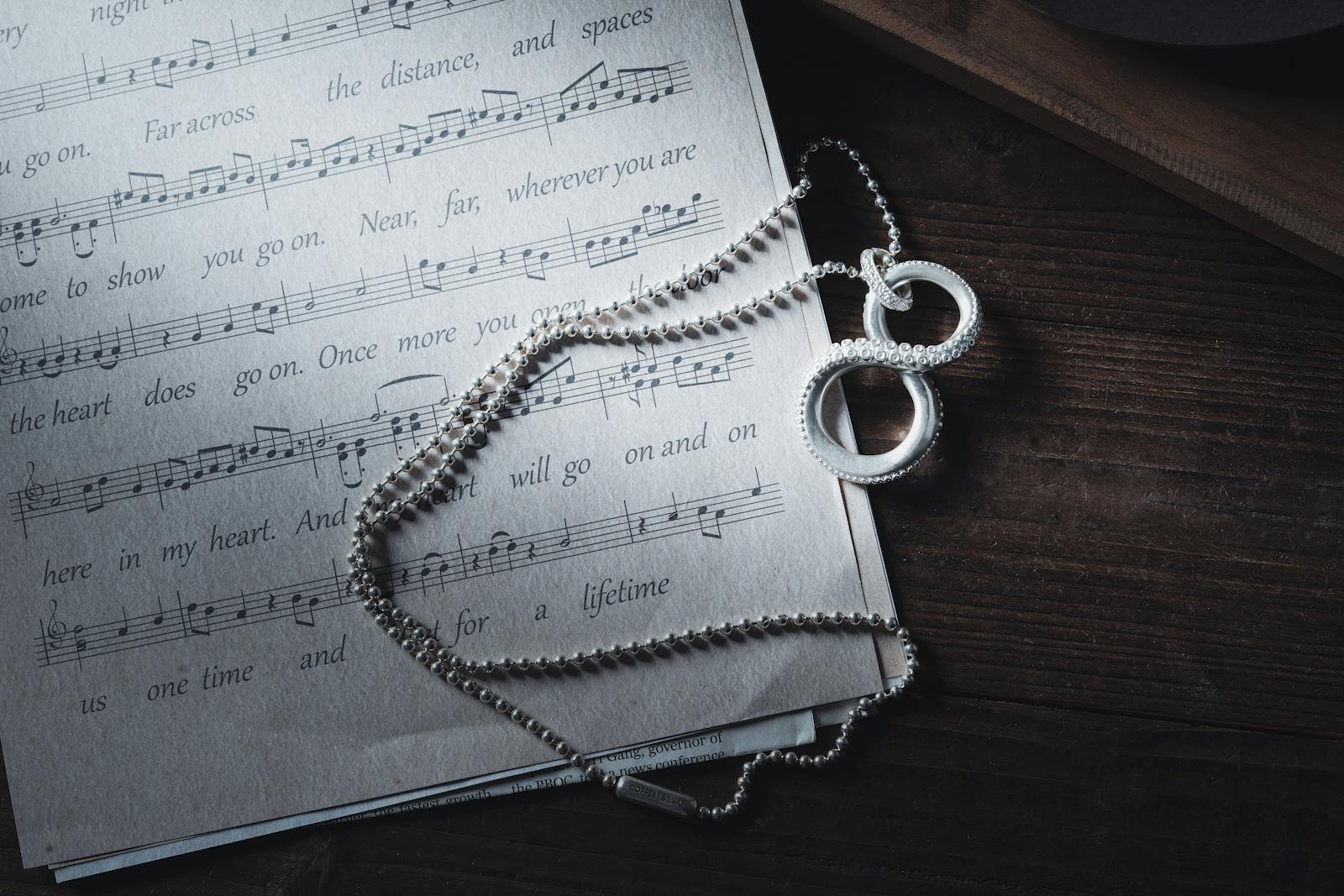 A close-up of a silver necklace on a music sheet featuring an octopus tentacle design, creating an artistic ambiance.