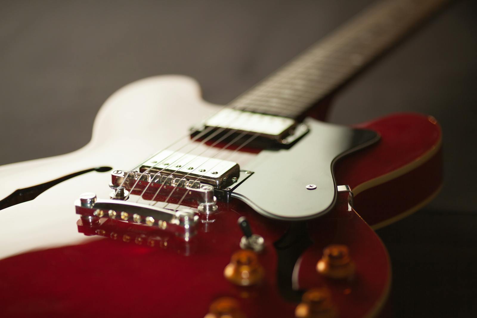 Detailed close-up of a red electric guitar showcasing the bridge and strings.