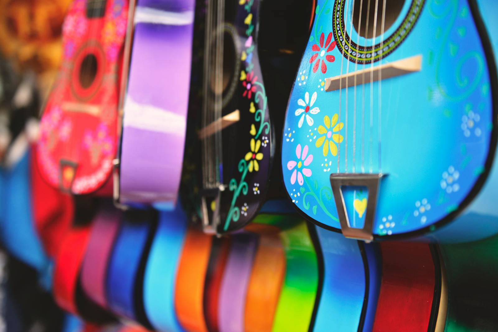 Vibrant close-up of artistically decorated acoustic guitars with floral patterns.