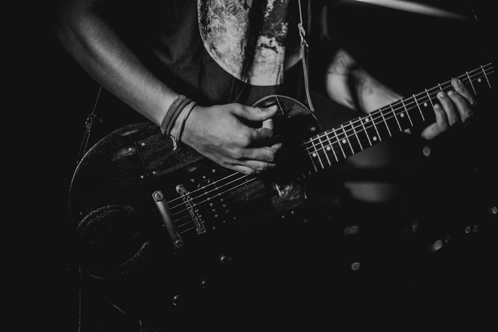 Black and white photo of a guitarist playing during a live performance.